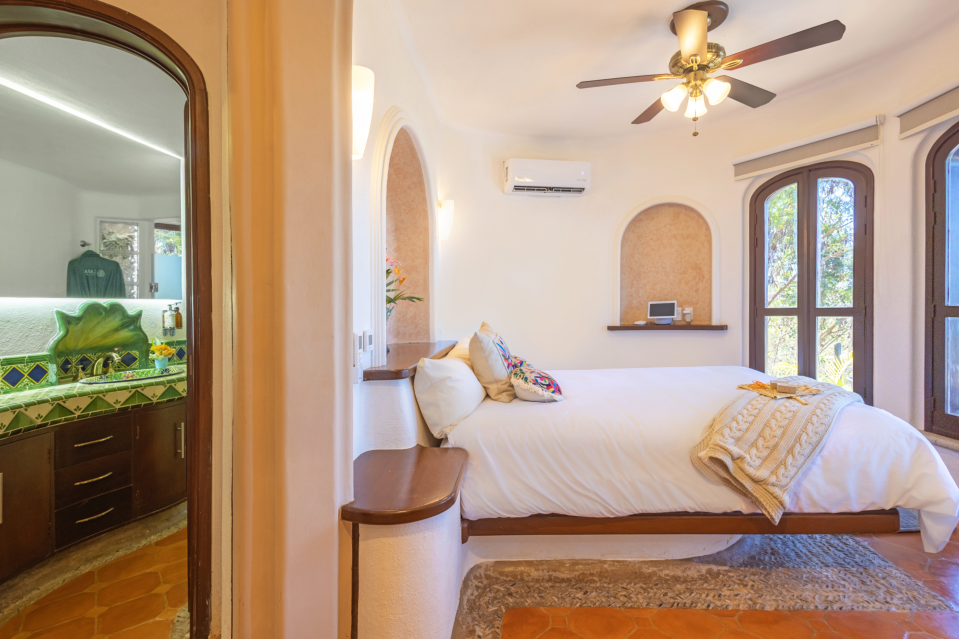 Cozy queen bed with colorful tropical bedding, surrounded by lush greenery in the Queen Room at Casa Ensueño.