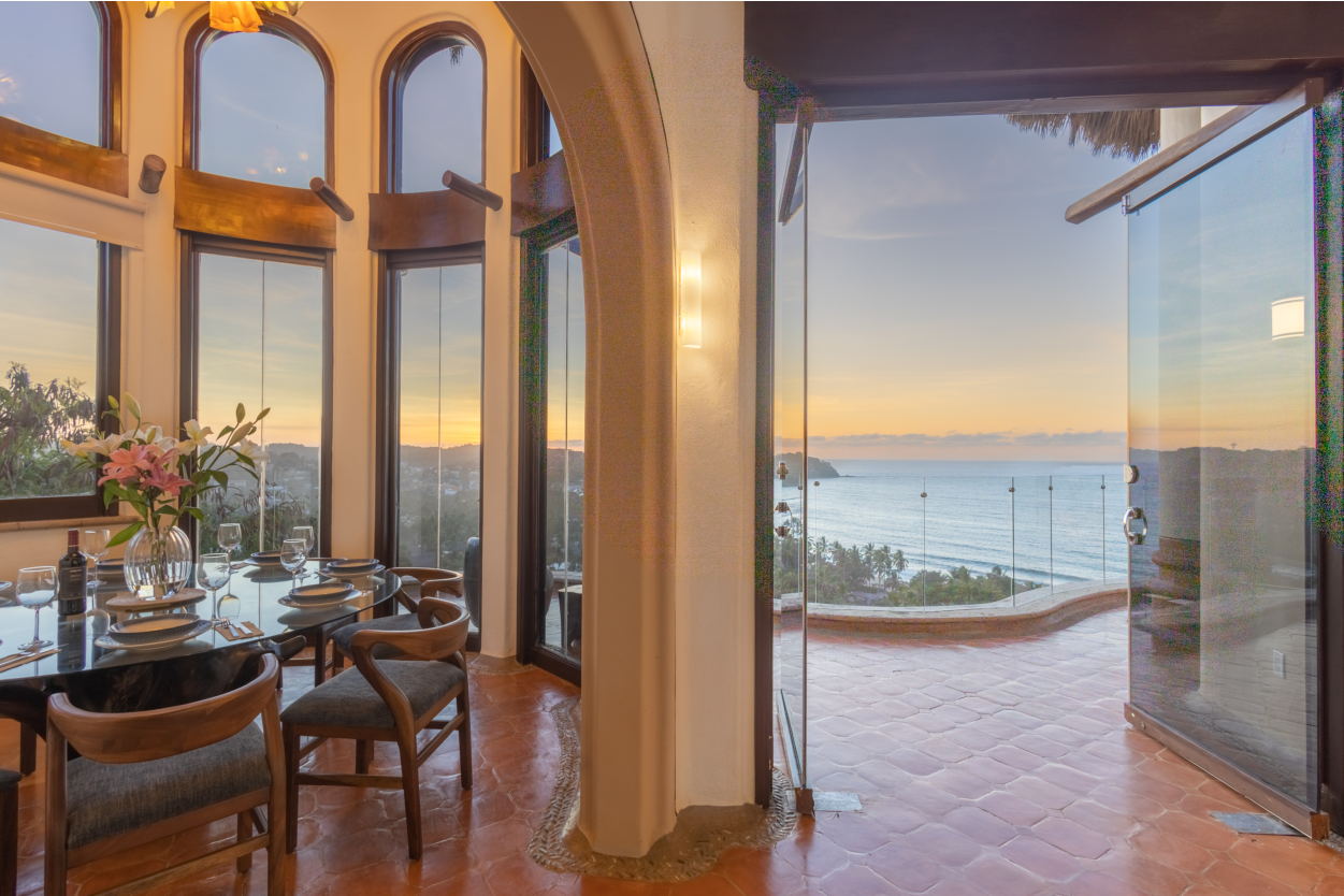 Elegant dining room with high ceilings and large windows showcasing breathtaking ocean views