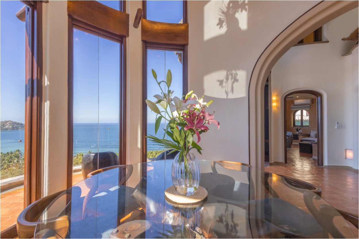 Stylish dining table set against a backdrop of soaring ceilings and panoramic ocean scenery.